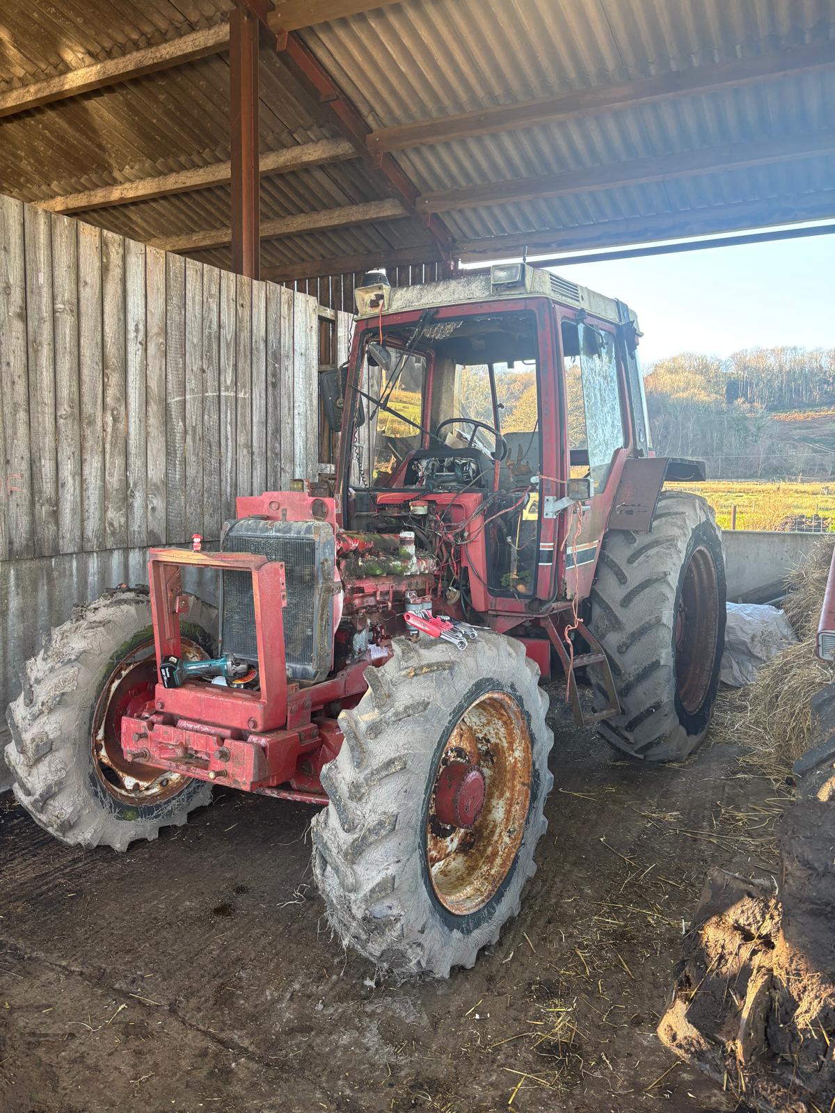 Case International tractor with the bonnet off and engine stripped down in a farm shed